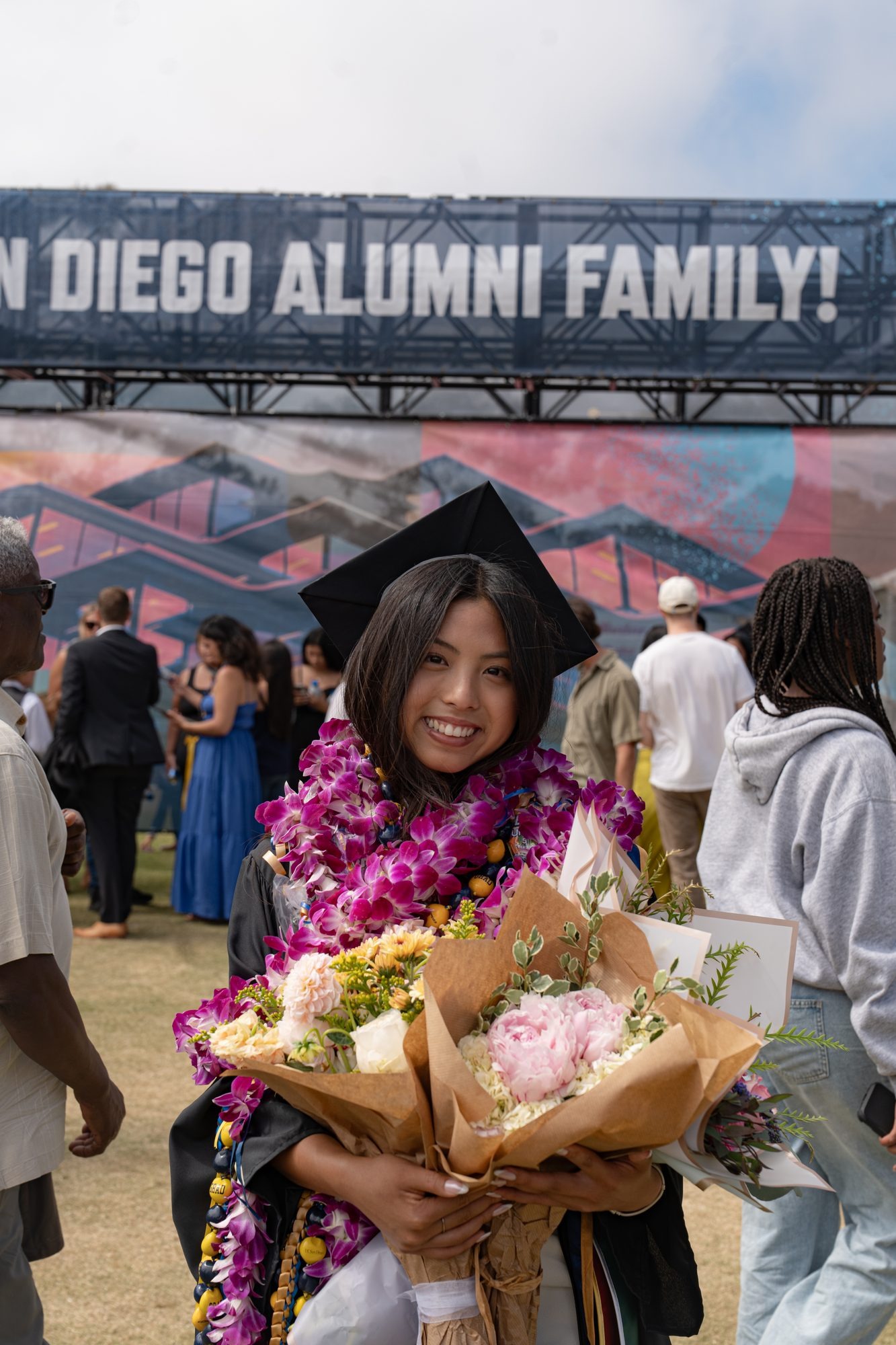 UCSD graduate with lei and bouquets